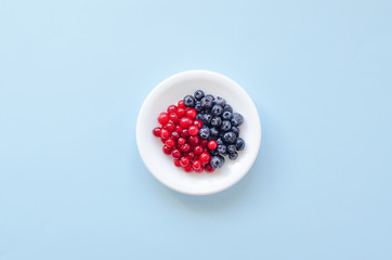 White saucer with berries on a blue background.