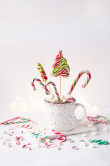 Close-up of mug with Christmas decor. Hot drink with marshmallow and candy canes. Selective focus, shallow depth of field