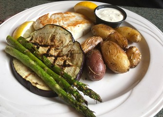 Baked fish with a serving of baked potatoes, eggplants and asparagus and tartar sauce.