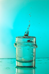Pure drinking water with splashes in a round glass on a light green background