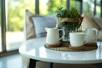 Closeup set of white ceramic cup and jug of tea and coffee with bokeh background.