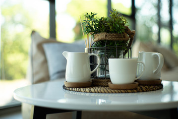 Closeup set of white ceramic cup and jug of tea and coffee with bokeh background.