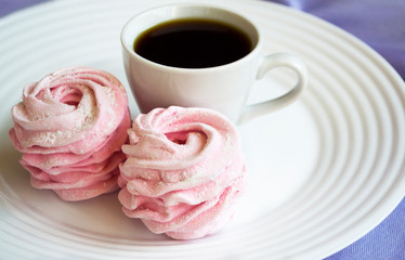 Homemade pink zephyr or marshmallow in white plate with cup of coffee. 