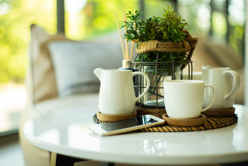 Closeup set of white ceramic cup and jug of tea and coffee with mobil phone.