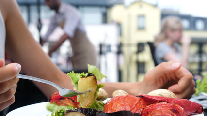 Woman eating a fork with grilled vegetables with fresh salad closeup in the summer outdoors