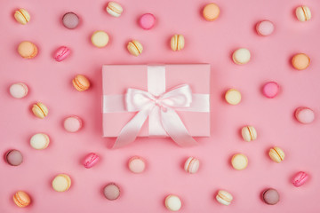 Gift box and macarons on pink background with copy space to write.