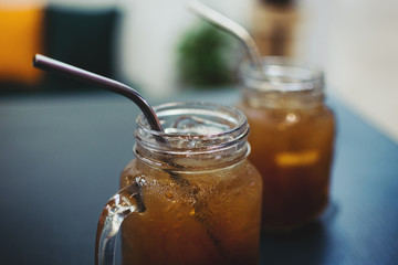 Iced tea in glass mason jars on wooden table, selective focus