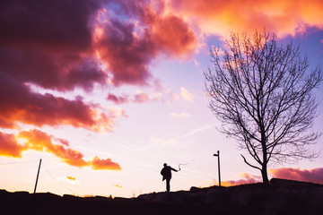 Man with whip silhouette, sunset sky.
