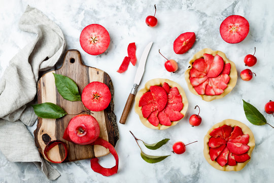 Baking apples pies over white marble table, top view. Cooking mini tarts with fresh red apples Baya Marisa.