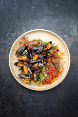 Traditional barbecue Italian blue mussel in tomato sauce with parsley and garlic in red wine sauce as top view on modern design plate with copy space