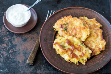 Vegetable fritters on a round ceramic plate. Fried potato cutlets or pancakes. The concept of fast food.