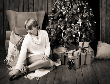 Sepia photo of a beautiful woman sitting in a room near Christmas tree