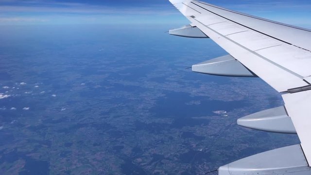 View through an airplane window. Airplane window view showing wing of a plane flying over Germany. Aerial footage. Travel concept.