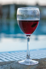 A glass of red wine by the pool