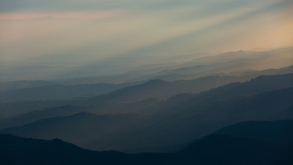 Fototapeta premium Beautiful sunset rays falling on top of a valley in Buila Vanturarita mountains, Romania