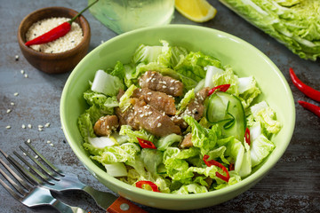 Diet menu, Vegan food. Healthy salad with Chinese cabbage, chicken, sesame and chili pepper on a dark stone table.