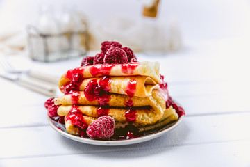 Stacked pancakes with fresh berries and icing sugar on light background