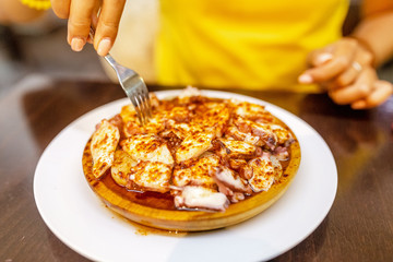 Happy woman eating delicious grilled octopus, spanish and mediterranean seafood cuisine concept