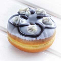 Fresh donut poured with icing and decorations, on a white wooden table