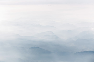 Fototapeta na wymiar Misty mountain ridges in alps with clouds, aerial view