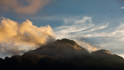 High mountain peaks in Romania covered in coloured clouds at sunset.
