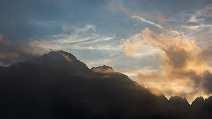 High mountain peaks in Romania covered in coloured clouds at sunset.