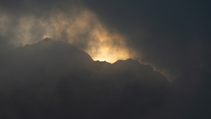 High mountain peaks in Romania covered in coloured clouds at sunset.