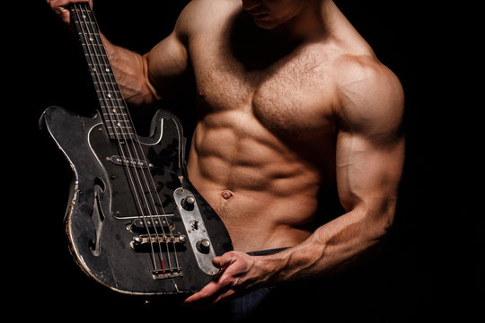 Guitar. Torso man. Play the guitar. Chest muscles, Six pack, ab, triceps. Music festival. Instrument on stage and band. Strong, muscular, muscles man, bodybuilding. Music concept. Electric guitar.