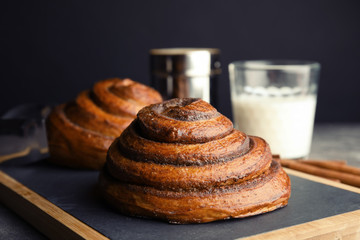 Board with baked cinnamon rolls on table, closeup