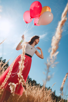 Pretty girl with many colored balloons in hand