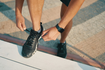 Sportsman ties his black sneakers