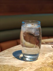 Clear glass of water on a table, with only the top of the glass in focus