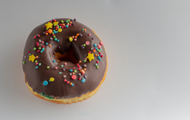 Fresh donut topped with glaze and decorated with colorful decorations on a white background