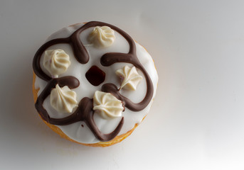 Fresh donut topped with glaze and decorated with colorful decorations on a white background