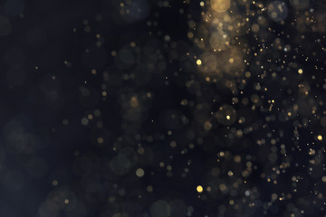 Fototapeta na wymiar Golden glitter with bokeh effect on dark background