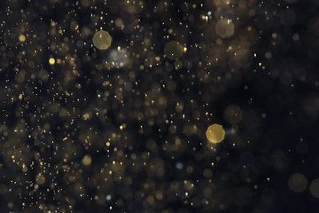 Golden glitter with bokeh effect on dark background