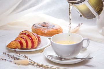 green tea with croissants on white wooden background