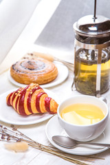 green tea with croissants on white wooden background