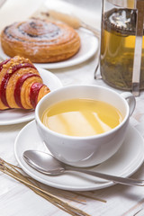 green tea with croissants on white wooden background