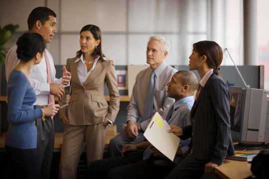 Business colleagues gathered around while attending a meeting in an office.