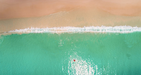 Aerial view of slim woman swimming on the swim ring  donut in the transparent turquoise sea in Seychelles. Summer seascape with girl, beautiful waves, colorful water. Top view from drone
