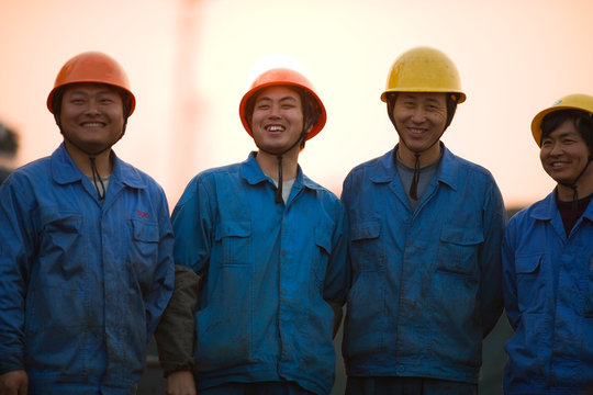 Portrait of mid-adult male construction workers standing on a shipping dock.
