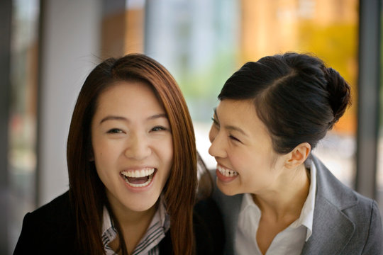 Portrait of two young adult woman laughing together.