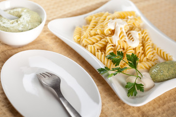Pasta in white plate, parsley, bowl with mayonnaise sauce