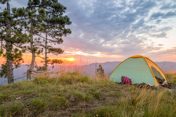 Fototapeta na wymiar Tent on the top of the mountain in sunrise with pine trees