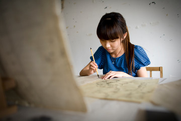 Teenage girl painting in an art room.