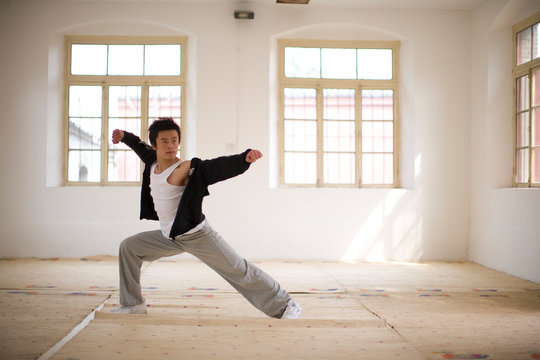 Teenage boy standing in a martial arts pose in a room.