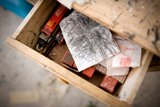 Stamps and a sketch sitting in a wooden draw.