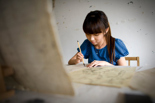 Teenage girl painting in an art room.