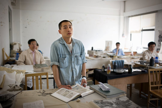 Portrait of a young adult man standing in an art classroom.